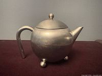 Right side view showing spout, knobbed lid, ball feet