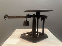 Full view of cast iron balance scale showing platform, beam arm, hanging weight