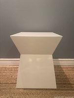 Front view of white geometric end table showing geometric shape