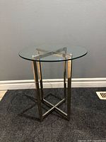 Front view of round glass side table showing chrome legs and X-brace