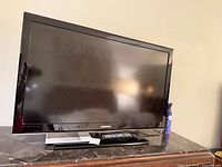 Front view of Samsung 40-inch LCD TV on stand with remote visible