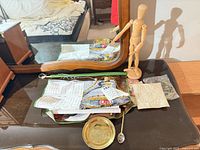 Lot overview showing artist mannequin, brass plate, spoon, cloth calendar and other small items on dresser
