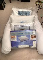 Overall view of U-shaped body pillow with stack of packaged and unpackaged pillows
