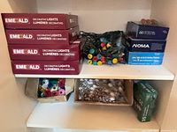 Shelf with four Emerald light boxes, loose multicolour lights, Noma 60 lights box, white-cover light strand and green box of 35 lights