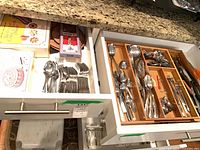 Open drawers showing grouped stainless flatware and pastry items