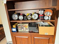 Shelf with eight flashlights, lanterns, compressor, crafting kit box, and cardboard box of tools