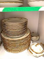 Stacks of plates, creamer, sugar bowl inside cabinet