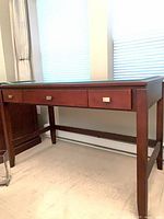 Full frontal view of maple finish desk showing drawers and glass top