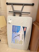 Table folded, wrapped in plastic with label visible