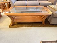 Front angled view of oak coffee table showing glass top and frame