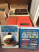 Boxes containing red Popular Mechanics volumes and two large reference books set in front