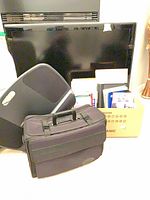 Lap desk, briefcase, cardboard box of stationery in front of TV