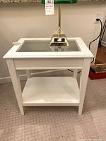 Front view of white side table showing glass top and shelf