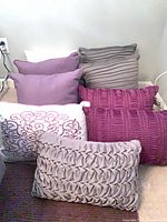 All nine pillows grouped against wall showing variety of colors and textures