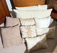 Nine pillows grouped: three paisley lumbar, four square pillows, two small rectangular pillows