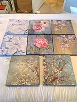 All eight square floral canvases laid out on bed