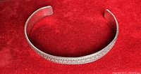 Full view of sterling cuff bracelet on red background