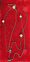 Full view of sterling silver flower station necklace on red background