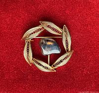 Front view of circular filigree brooch with central polished stone