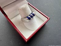 Ring in display box, frontal view showing blue inlays