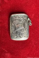 Front of engraved sterling silver vesta case showing monogram and scroll design