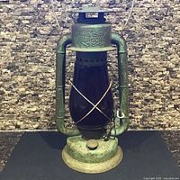 Full front view of Beacon kerosene lantern showing red glass globe and green metal frame
