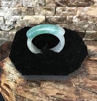 Front angled view of translucent jade archer's ring on display pad