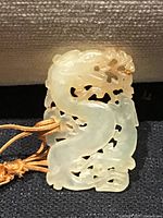 Front view of carved jade dragon pendant with cord