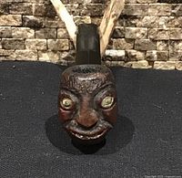 Front view of carved face bowl showing green eyes and carving detail