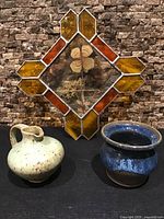 Overall view of stained glass panel with two pottery pieces