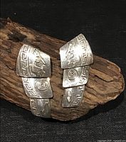 Front view showing both articulated earrings with Kokopelli and geometric designs
