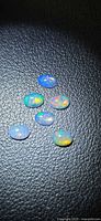 Six oval cabochon opals on black textured surface