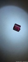 Octagon-cut rubellite gemstone under spotlight view