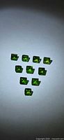 Nine green square cut gemstones arranged in triangle formation