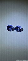 Pair of round violet-blue gemstones on neutral background