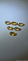 Six oval golden citrine gemstones arranged on neutral background