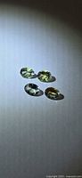 four oval lemon lime tanzanite gemstones angled under spotlight