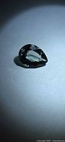 Pear cut blue-green tourmaline gemstone in spotlight