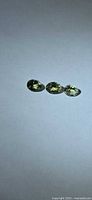 Three oval pale yellow-green faceted gemstones