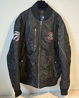 Front view of black Toronto Raptors bomber jacket hanging