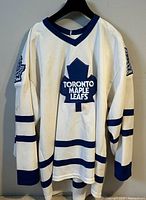 Front view of white CCM Toronto Maple Leafs jersey hanging