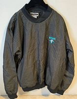 Front view of black-grey grid pattern Inner Harbor jacket with teal LYNX logo