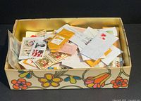Top view of floral box filled with assorted Canadian and US stamps