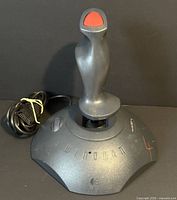 Front view of Logitech WingMan joystick showing grip, trigger, base buttons, cable