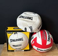 Two white Spalding Chameleon volleyballs and red-white Fusion Extreme volleyball with one retail box visible