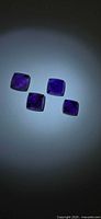 Four square sugarloaf cut amethyst gemstones shown under direct light