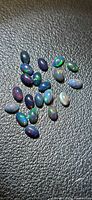 Group of oval black opal cabochons on textured surface