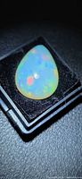 Pear-shaped Ethiopian opal cabochon in box showing play of colour
