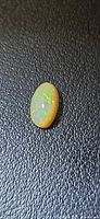 Oval caramel opal cabochon on textured background