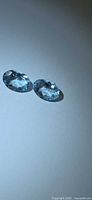 Pair of light blue oval aquamarines on neutral background
